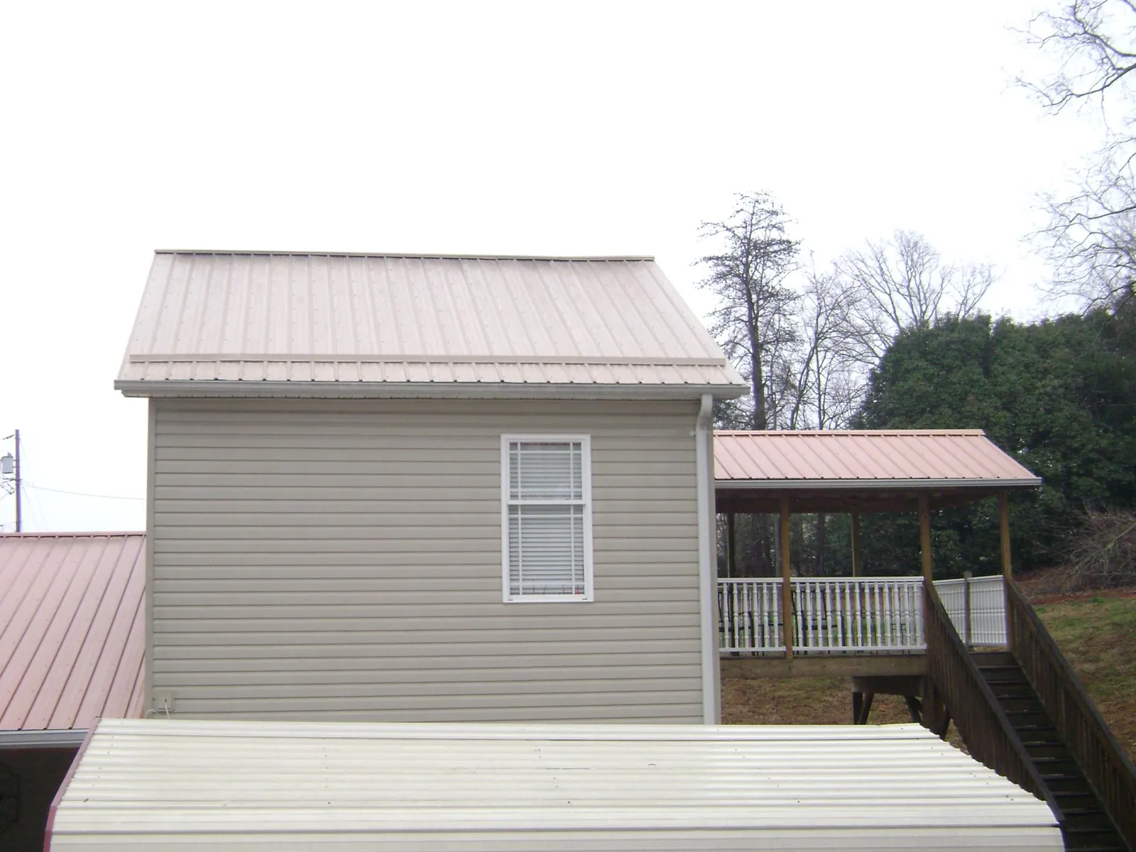 Tan metal roofs on a two story addition and attached porch, from a Roof Replacement job in Sparks